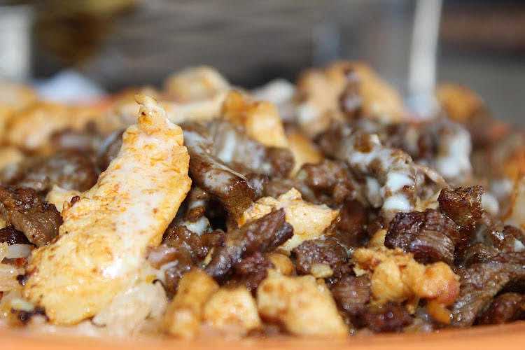 Close-up of a plate of cheesy beef and chicken nachos with a blurred background.