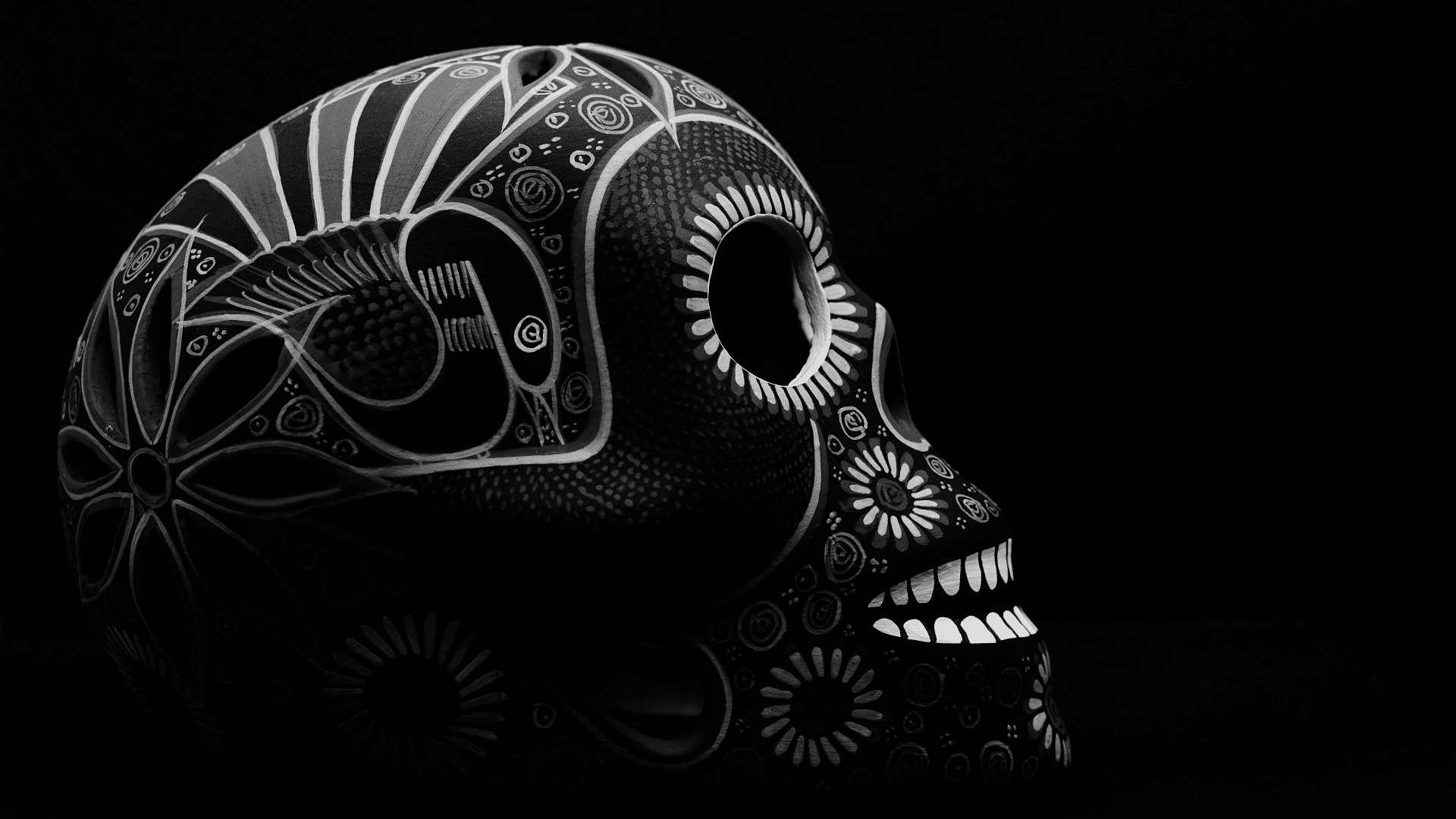 A decorative skull with intricate patterns on a black background.