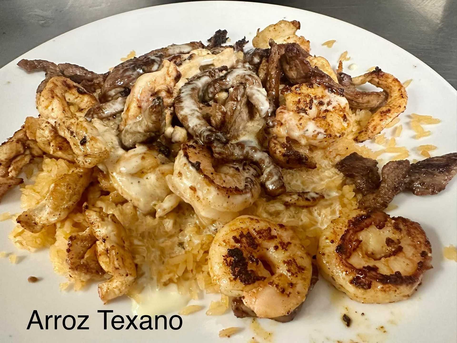 A plate of Arroz Texano with grilled shrimp, chicken, beef, and melted cheese.